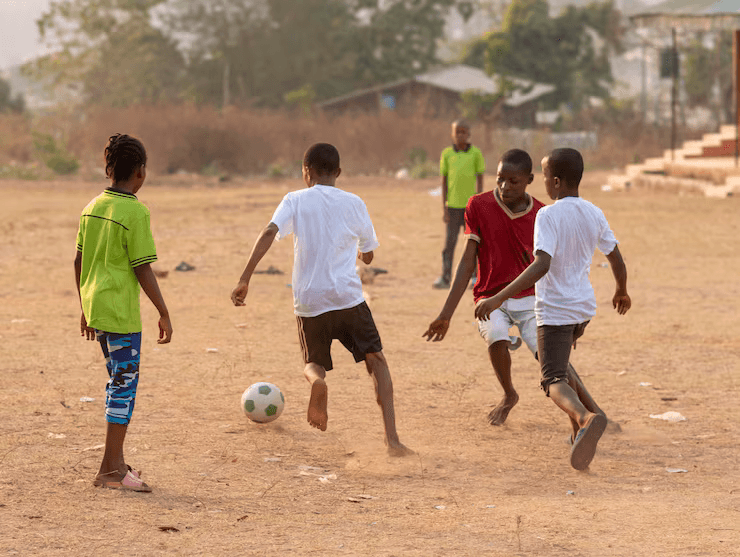 Young athletes playing football on a dirt field — talent is global but access is limited